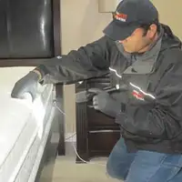 Bed bug inspection technician checking a mattress and bed frame for signs of infestation in Tempe, AZ