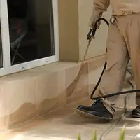 General pest control technician spraying exterior perimeter around a home in Tempe, AZ