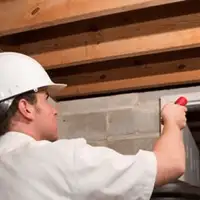 Termite inspection technician checking a basement wall and framing for termite activity in Tempe, AZ